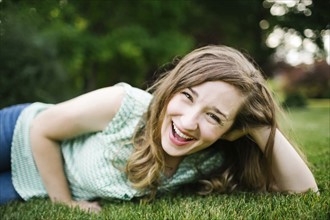 Portrait of woman lying on grass and laughing