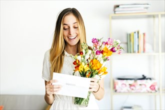Beautiful woman reading letter and holding flowers
