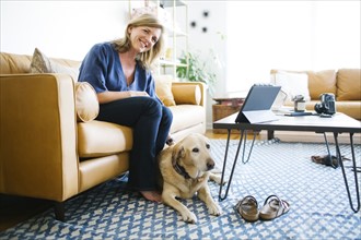 Woman stroking Labrador Retriever in living room