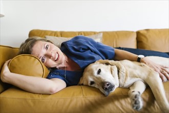 Woman and Labrador Retriever lying down on sofa