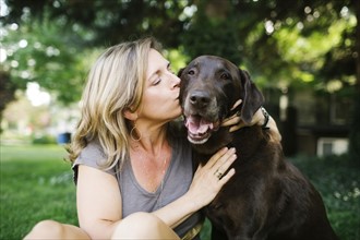 Portrait of woman kissing Labrador Retriever