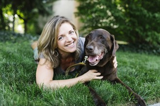 Portrait of smiling woman lying on grass with Labrador Retriever