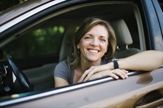 Portrait of smiling woman looking through car window