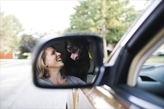 Woman and Labrador Retriever reflecting in side-view mirror