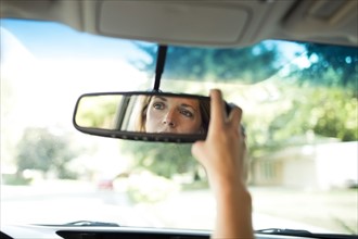 Woman adjusting rear-view mirror in car