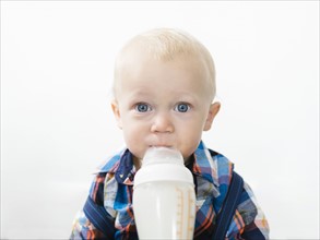 Studio shot of boy (12-17 months) drinking from baby bottle