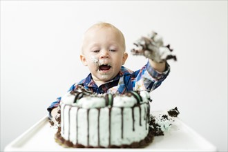 Baby boy (12-17 months) eating birthday cake