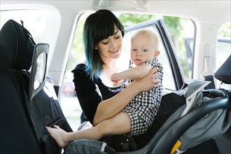 Mother holding baby boy (12-17 months) in car