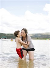 Mother kissing son (4-5) while wading in lake