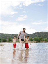 Mother with sons (4-5, 6-7) wading in lake