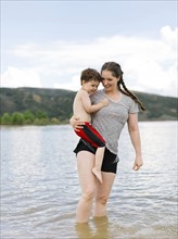 USA, Utah, Park City, Mother carrying son (4-5) while wading in lake