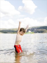 Boy (4-5) jumping in lake