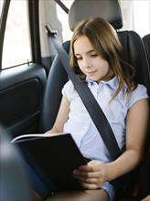 Girl ( 8-9) sitting in car and reading book