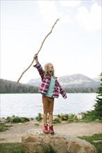 USA, Utah, Midway, Boy with stick (6-7) standing on rock by lake