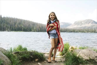 USA, Utah, Midway, Portrait of girl (8-9) wrapped in us flag standing by lake