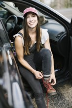 Woman sitting in car and tying shoes