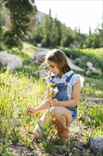Girl (8-9) picking wildflowers in meadow