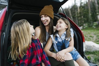 Woman with son (6-7) and daughter (8-9) in back of car
