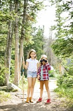 Girl (8-9) and boy (6-7) standing in forest