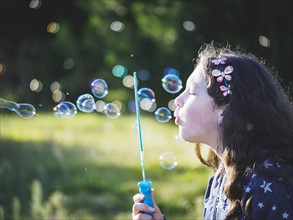 Girl (10-11) blowing bubbles