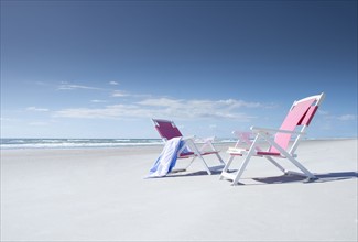 Two deckchairs on empty beach