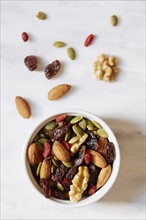 Bowl of nuts and raisins on white background