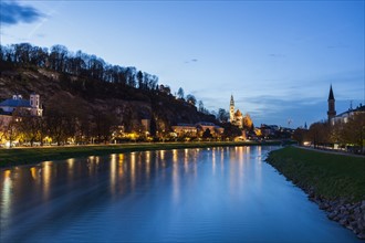 Austria, Salzburg, River and illuminated riverbank at dusk