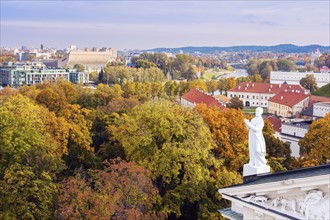 Lithuania, Vilnius, Statue on roof with cityscape in background