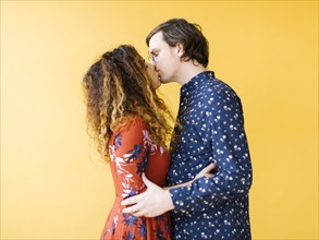 Couple kissing against yellow background