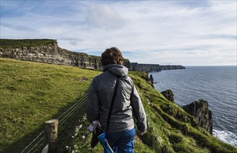 Ireland, County Clare, Woman walking along Cliffs of Moher
