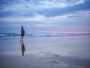Australia, New South Wales, Woman standing on beach at dusk