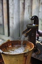 Water from water pump pouring into bucket