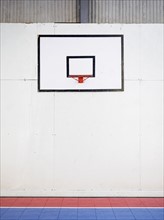 Empty basketball court with basketball hoop hanging on wall