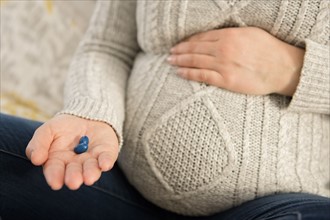 Pregnant woman holding pills in hand
