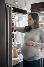 Pregnant woman looking into refrigerator