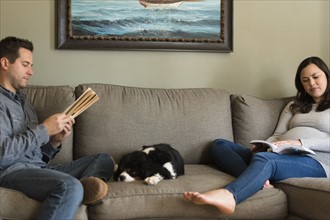 Mid adult couple relaxing on sofa with puppy in middle