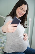 Pregnant woman taking selfie with smart phone