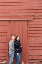 Mid adult couple standing in front of red barn