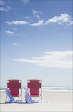 Red chairs in beach, sea in background