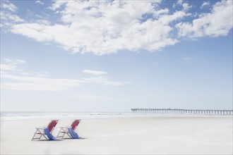 Deck chairs on sandy beach by Atlantic Ocean