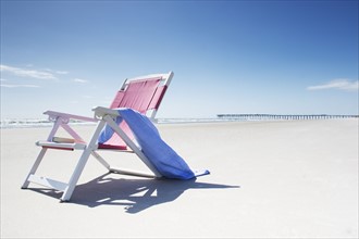 Deck chair with towel on sandy beach by Atlantic Ocean