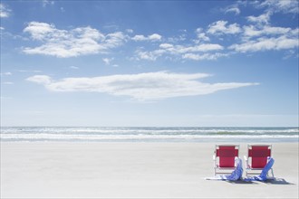Deck chairs with towels on sandy beach by Atlantic Ocean