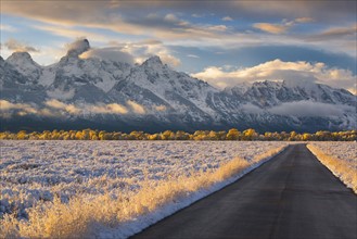 USA, Wyoming, Country road and Teton Range at sunset