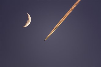 Plane flying next to moon at dusk