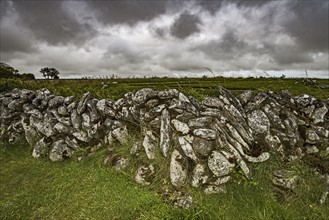 Ireland, County Clare, Burren, Stone wall against stormy sky