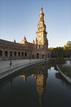 Spain, Andalusia, Seville, Tower in Plaza de Espana reflected in water