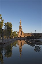 Spain, Andalusia, Seville, Tower in Plaza de Espana reflected in water