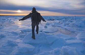 USA, Massachusetts, Cape Cod, Eastham, Man balancing on sea ice at dusk
