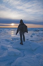 USA, Massachusetts, Cape Cod, Eastham, Man balancing on sea ice at dusk