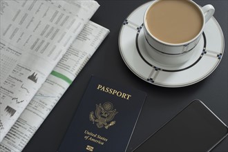 Passport, newspaper, smart phone and coffee on table